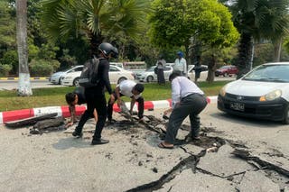 Motorists pick up pieces of a damaged road in Naypyidaw
